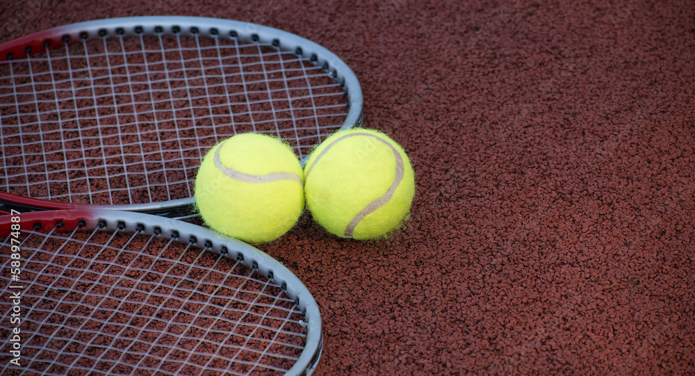 Two tennis balls and two racquets on tennis court