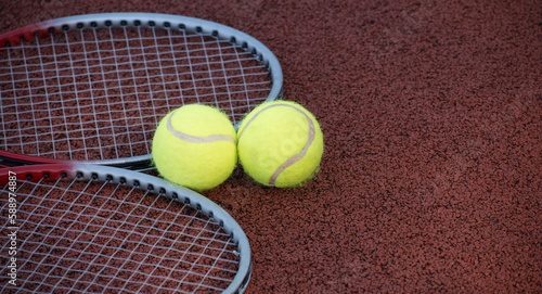 Two tennis balls and two racquets on tennis court © NetPix