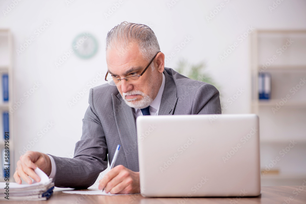 Old male employee working in the office Old male employee working in the office