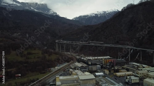 Aerial view of an Industrial area surrounded by dark mountains. Train railroad and main highway on a viaduct. photo