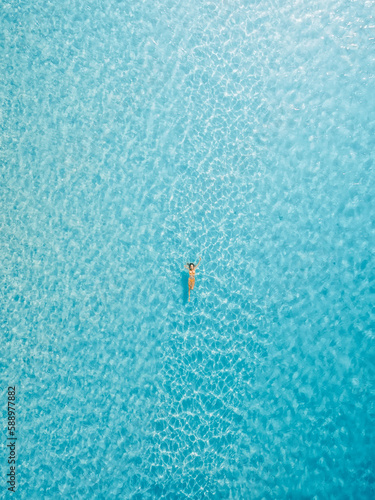 Woman floating in blue ocean on her vacations. Aerial view, top view
