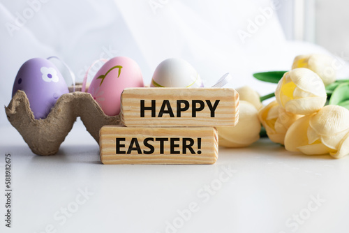 Colorful decorative eggs and HAPPY EASTER text close-up, against the background of a white flowers