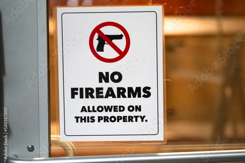 Close up of No firearms allowed on property sign in store window banning gun of private property.