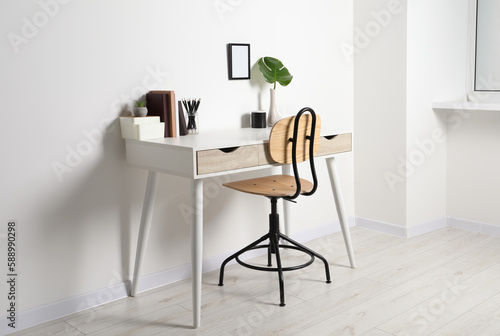 Comfortable workplace with white desk near wall indoors