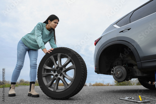 Young woman changing tire of car on roadside © New Africa