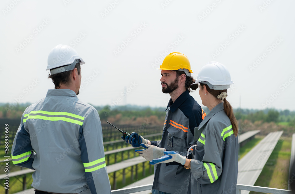 On the rooftop of a large solar energy storage station building A team of electric power engineers inspecting solar panels that have been installed on hundreds of acres of fields. On the rooftop of a large solar energy storage station building A team of electric power engineers inspecting solar panels that have been installed on hundreds of acres of fields.