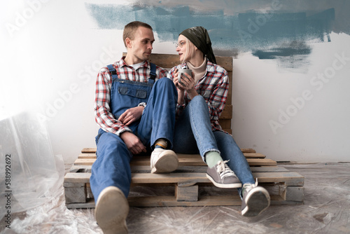 Happy young couple holding cup of tea and resting from home repair. Repair  interior design  renovation and home