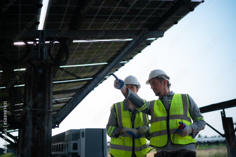 A team of electrical engineers is inspecting and maintaining solar panels at a solar panel site in the middle of a hundred acre field. A team of electrical engineers is inspecting and maintaining solar panels at a solar panel site in the middle of a hundred acre field.