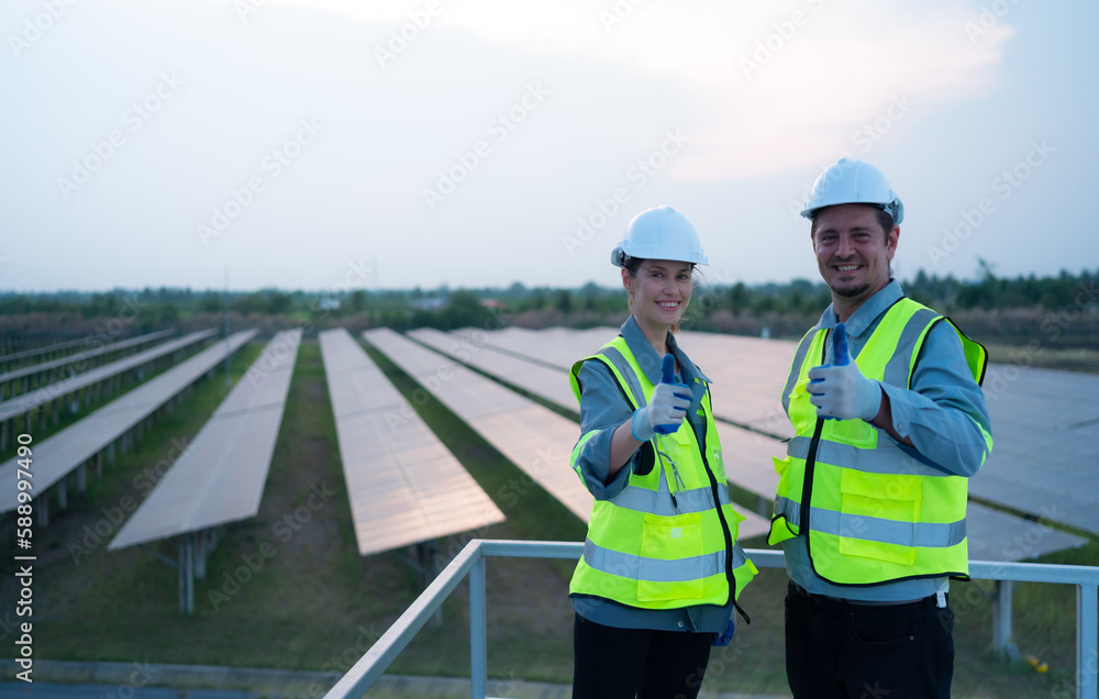 A team of electrical engineers inspecting solar panels in a hundred acres of grass on the rooftop of energy storage station, in the evening after completing the daily work tasks with the setting sun A team of electrical engineers inspecting solar panels in a hundred acres of grass on the rooftop of energy storage station, in the evening after completing the daily work tasks with the setting sun