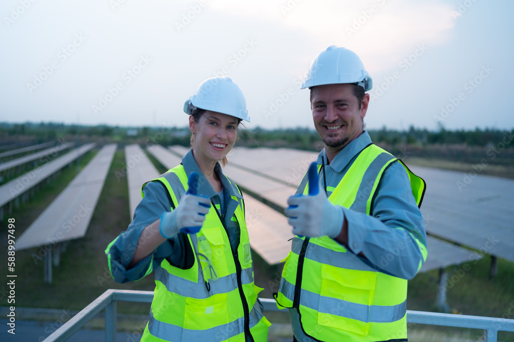 A team of electrical engineers inspecting solar panels in a hundred acres of grass on the rooftop of energy storage station, in the evening after completing the daily work tasks with the setting sun A team of electrical engineers inspecting solar panels in a hundred acres of grass on the rooftop of energy storage station, in the evening after completing the daily work tasks with the setting sun