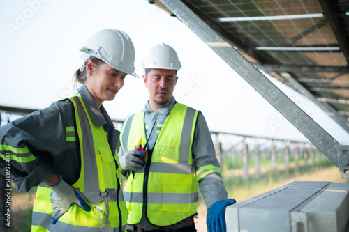 A team of electrical engineers is inspecting and maintaining solar panels at a solar panel site in the middle of a hundred acre field.