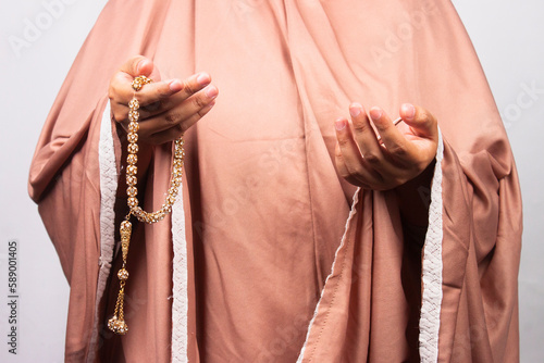 Islamic moslem woman praying with crystal tasbih wearing traditional dress photo