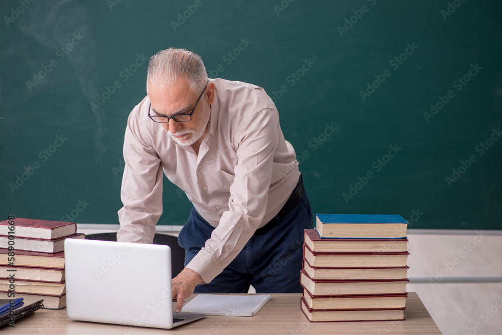 Old male teacher sitting in the classroom