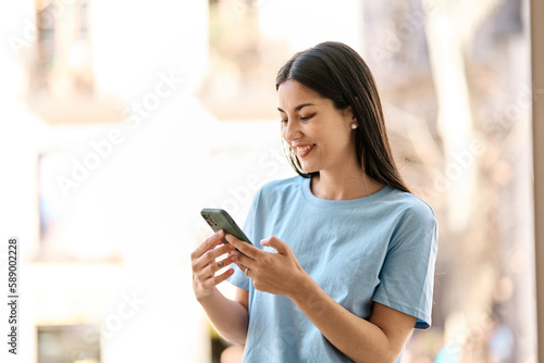 Woman smiling while using the mobile phone outdoors