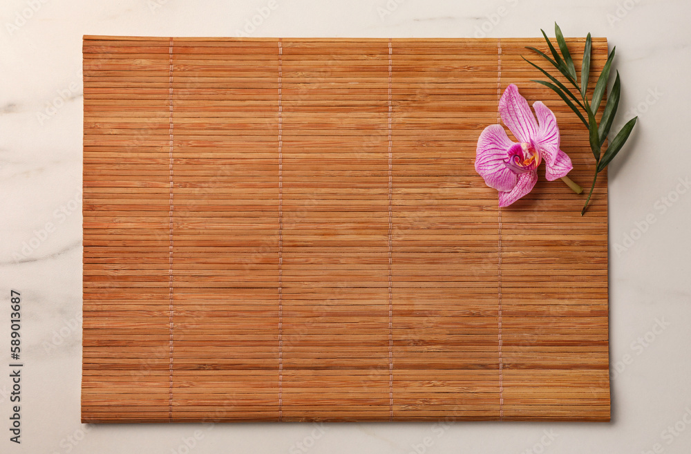 Bamboo mat, green leaf and orchid flower on white marble table, top view. Space for text Bamboo mat, green leaf and orchid flower on white marble table, top view. Space for text