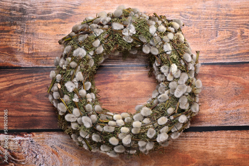 Wreath made of beautiful willow flowers on wooden table, top view