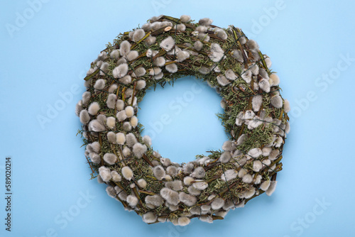 Wreath made of beautiful willow flowers on light blue background, top view