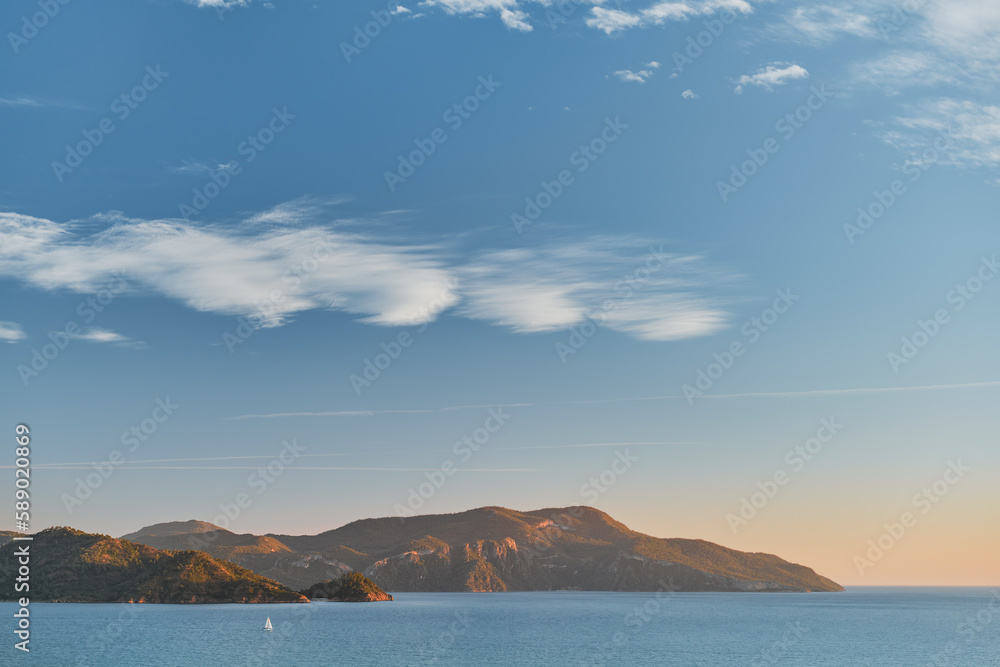 Beautiful sunset on the Aegean Sea with islands, mountains and a sailboat. Seascape, travel and vacation in nature, idea for a background or advertising sea voyages