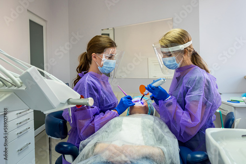 Beautiful girl in a patient's bib and orange UV goggles in a dental clinic. photo