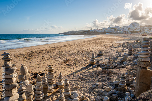 Stone balancing arrangements of stacked stones on Praia da Luz beach, created in a meditative state, with the tranquil evening sea and sky in the background, offering a serene and peaceful atmosphere.