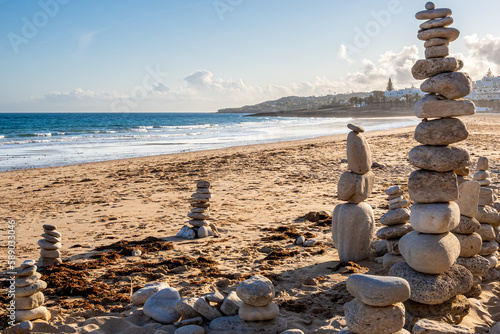 A serene evening view of Praia da Luz beach, with stacked rocks creating a mesmerizing environmental art piece in the foreground, offering a perfect opportunity for balance and meditative reflection. photo