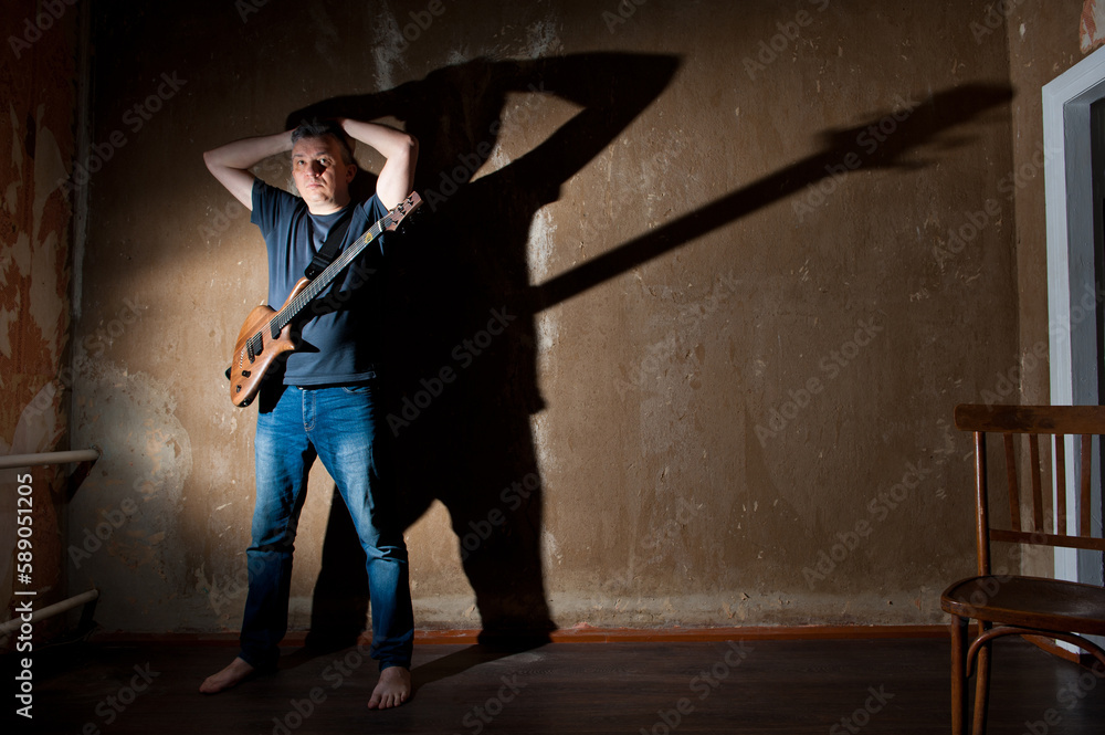 Male musician with an electric guitar on the background of an old wall. Male musician with an electric guitar on the background of an old wall.