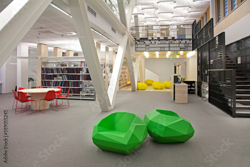 A healthcare college library with open spaces, green chairs and book stacks. A modern light and airy building.  photo