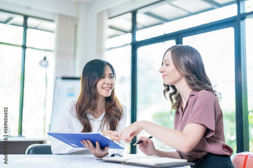 Smiling businesswoman working together on contract document, happy colleague meeting for planning new project in office Smiling businesswoman working together on contract document, happy colleague meeting for planning new project in office