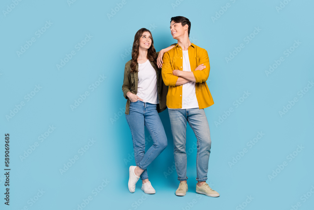 Full length photo of two smiling satisfied couple folded hands looking each other advertisement new cafeteria menu isolated on blue color background Full length photo of two smiling satisfied couple folded hands looking each other advertisement new cafeteria menu isolated on blue color background