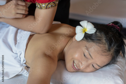 Massager doing Thai massage with elbow to Asian woman in Spa and Massage shop