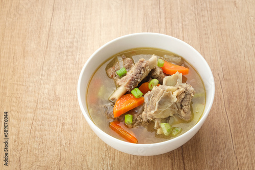 Sop Iga (Beef ribs soup) made from ribs, carrots, leeks.  Served in white bowl. Indonesian food
