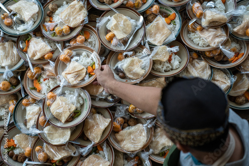 a man prepares takjil food at the jogokariyan mosquea man preparing takjil food at the jogokariyan mosque, so many stacks of plates filled. photo