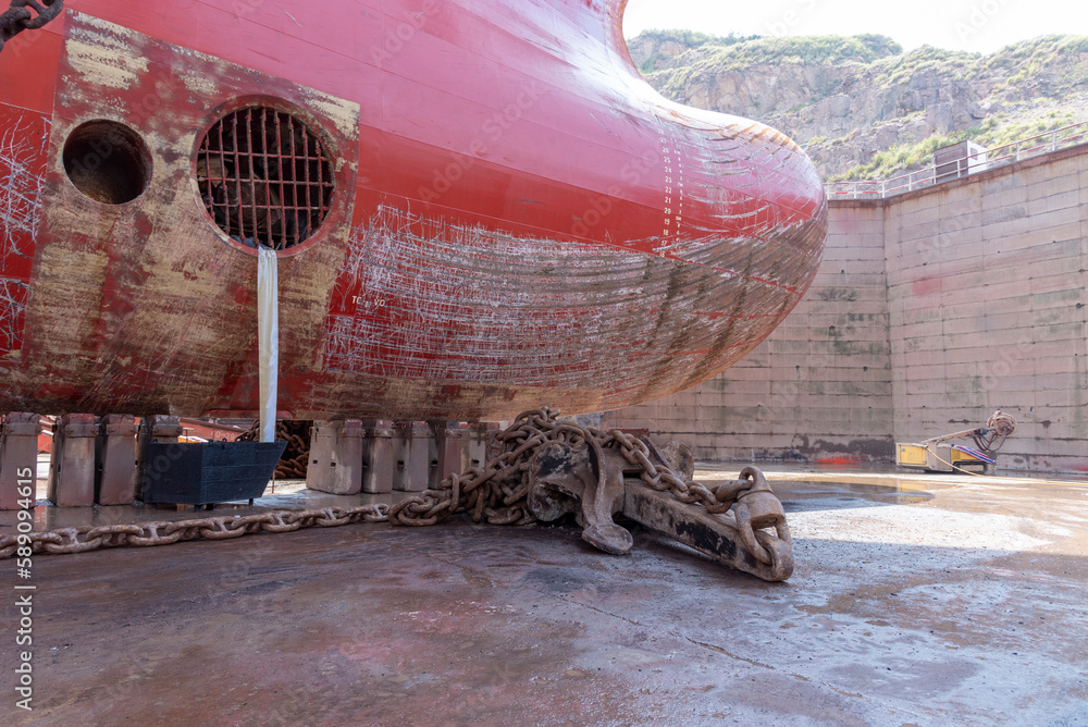 Close up view on the bulbous bow of the big container ship. She is inside dry dock for scheduled maintenance and painting. 