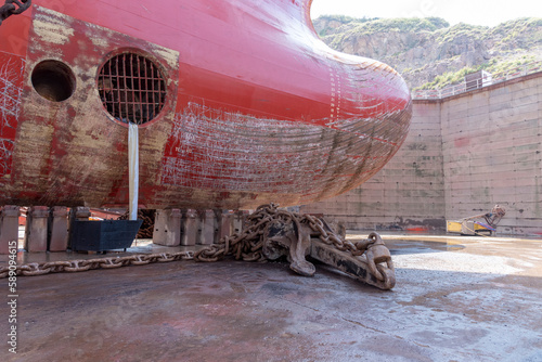 Close up view on the bulbous bow of the big container ship. She is inside dry dock for scheduled maintenance and painting. 