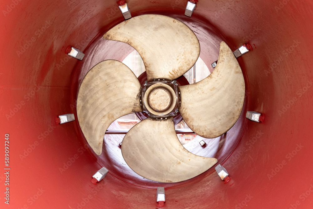 View on the stern thruster propeller of the big container ship. Ship is in the dry dock for scheduled maintenance and painting.