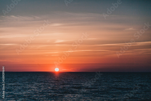 Sun set with orange and blue gradient sky windy weather clouds lake sea waves