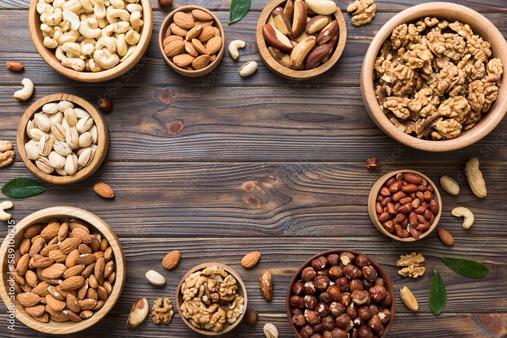 mixed nuts in wooden bowl. Mix of various nuts on colored background. pistachios, cashews, walnuts, hazelnuts, peanuts and brazil nuts