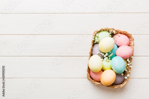 Happy Easter composition. Easter eggs in basket on colored table with gypsophila. Natural dyed colorful eggs background top view with copy space