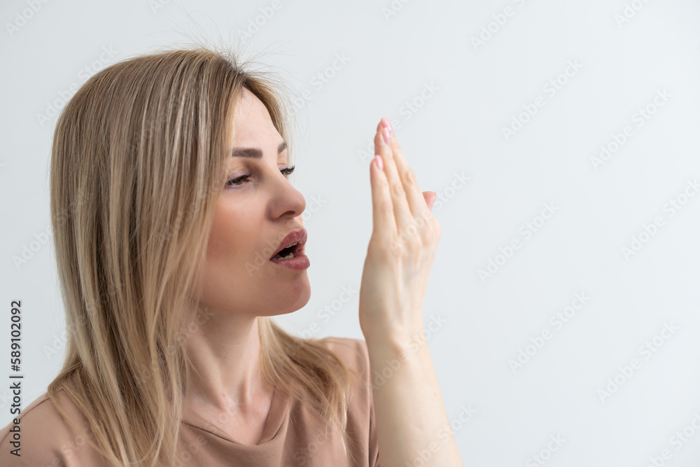 young woman checking her breath with her hand young woman checking her breath with her hand
