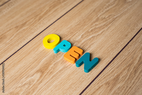 Colorful wooden letter displaying "Open" on wooden background. Business idea for opening businesses. 