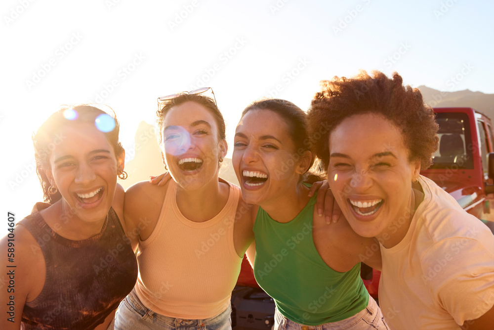 Portrait Of Smiling Female Friends Standing By Car Having Fun On Road Trip Through Countryside
