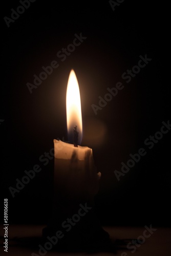 Vertical shot of a candle in the dark background.