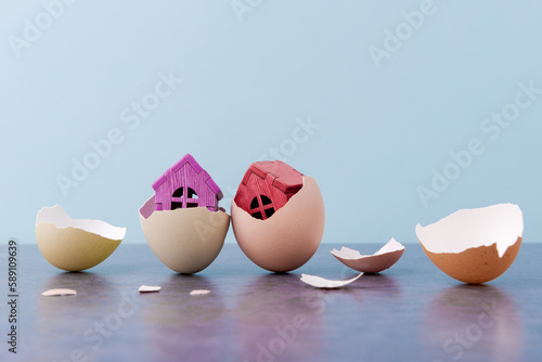 Tiny houses in eggs shell over blue background with copy space. Conceptual Easter greeting card