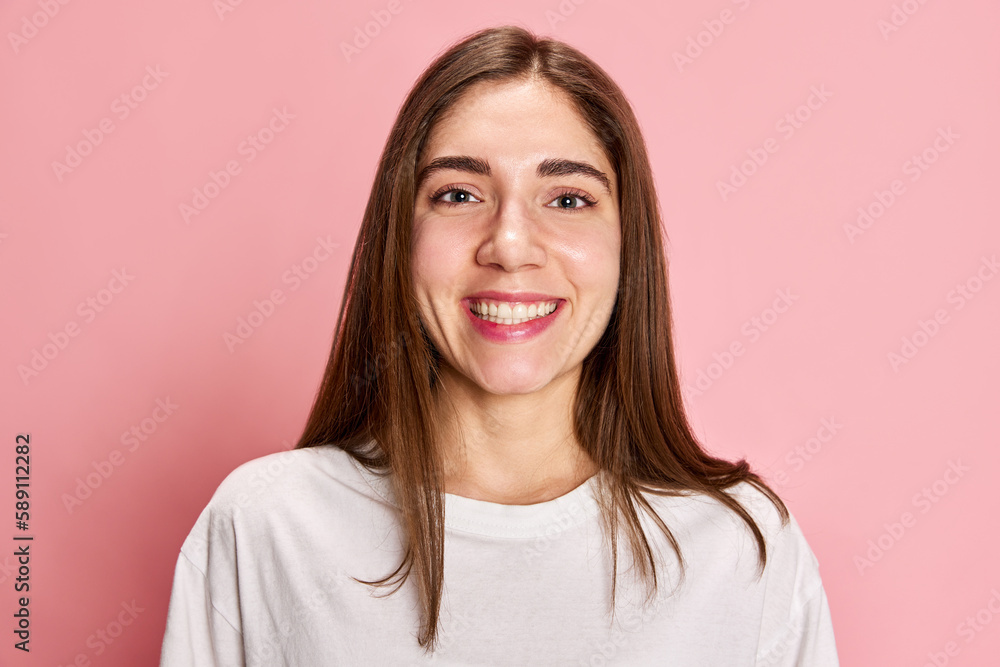 Portrait of happy, smiling, young girl in casual white t-shirt posing against pink studio background. Feeling good. Positive mood. Concept of youth, emotions, facial expression, lifestyle Portrait of happy, smiling, young girl in casual white t-shirt posing against pink studio background. Feeling good. Positive mood. Concept of youth, emotions, facial expression, lifestyle