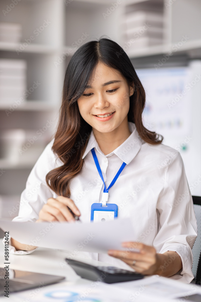 Charming Young asian businesswoman sitting on laptop computer in the office, asian employee business making report calculating balance Internal Revenue Service checking document. Charming Young asian businesswoman sitting on laptop computer in the office, asian employee business making report calculating balance Internal Revenue Service checking document.