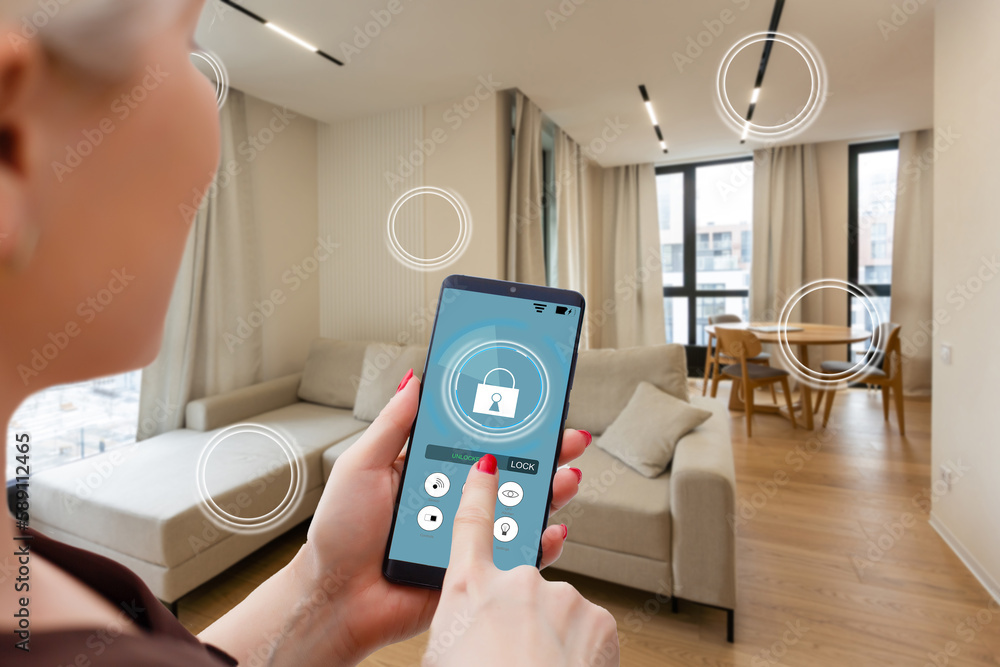 Home temperature, safety and environment control on mobile app. Smart phone in woman hand. Living room in background Home temperature, safety and environment control on mobile app. Smart phone in woman hand. Living room in background