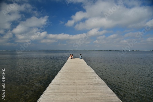 View of the sea and people sitting on the dock.