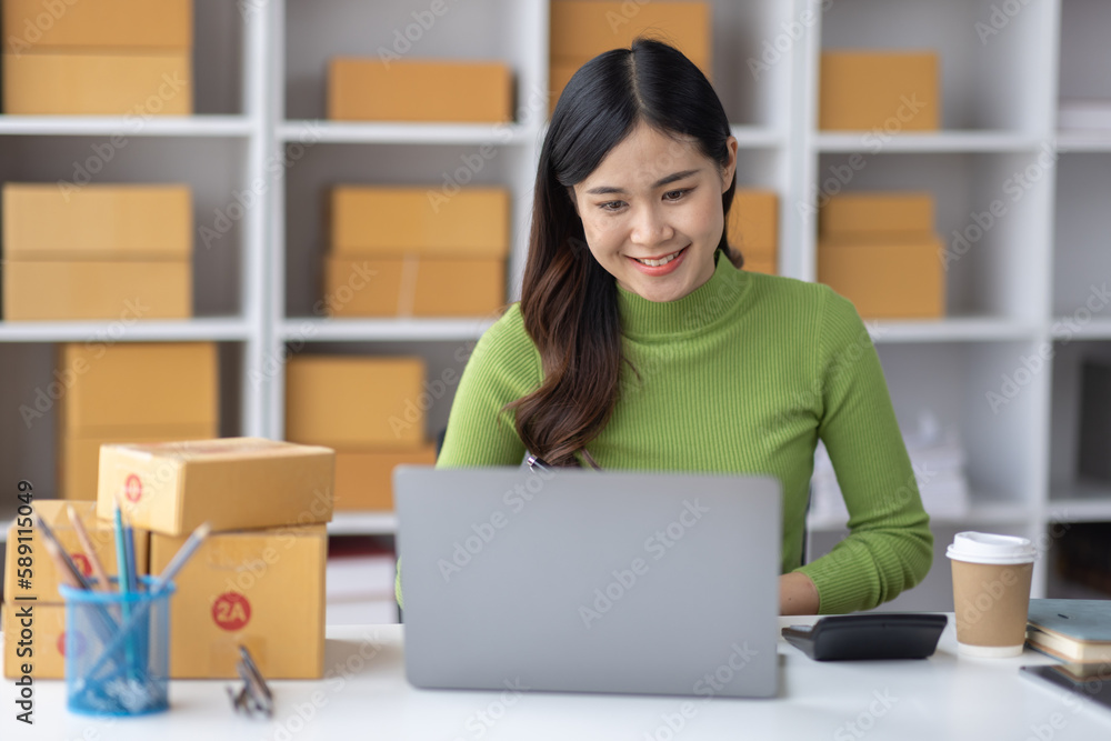 Startup SME small business entrepreneur freelance Asian woman using a laptop with box merchant seller checking customer address order confirming parcel SME delivery idea concept. Startup SME small business entrepreneur freelance Asian woman using a laptop with box merchant seller checking customer address order confirming parcel SME delivery idea concept.
