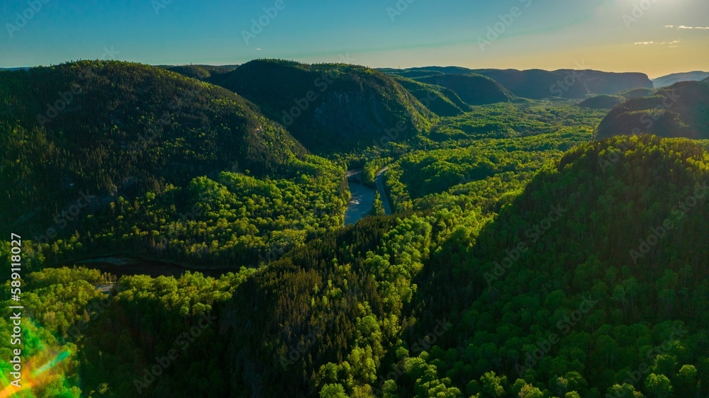 Naklejka premium Narrow river in Sainte-Marguerite Valley Forest at sunset in Quebec, Canada