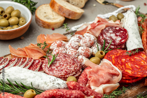 Salami, sliced ham, sausage, prosciutto, bacon, toasts, olives. Meat antipasto platter and red wine, Food recipe background. Close up